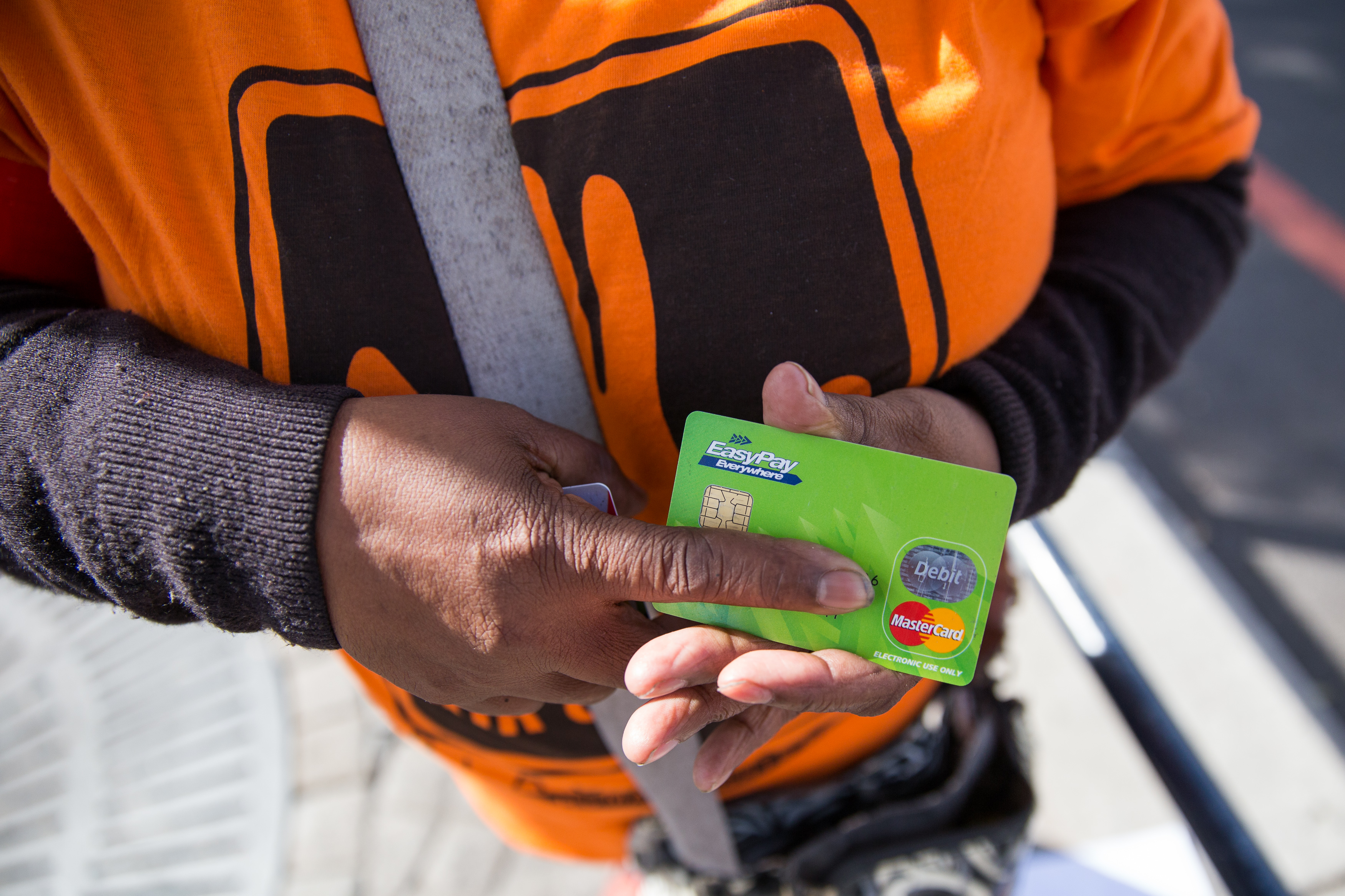 A social grant beneficiary holds on to her old Sassa card during a picket on social grants at Parliament earlier. Beneficiaries can now swop these cards for new cards to receive grant payments through the South African Post Office.  Photo: Ashraf Handricks/GroundUp